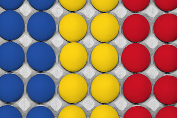 Chicken eggs painted in the style of the Romania flag. Chicken eggs in carton box. Top view eggs background.