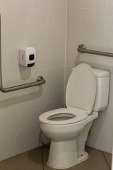 empty toilet for background. Toilet with handrails for the disabled. Focus on the lid of the toilet. Toilet seat decoration in bathroom interior. 