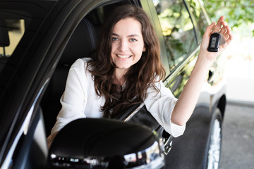 Attraktive junge Frau freut sich über ein neues Auto 