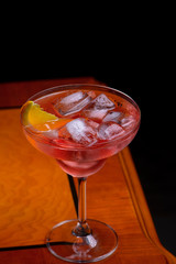 Negroni cocktail with orange slice on classic old-fashioned wooden table with dark background