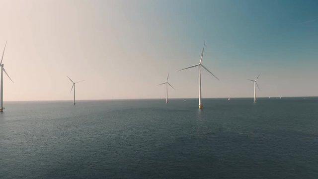 Aerial shot of Wind Farm Turbines In Sea in The Netherlands, Generating Green Energy. Sailing boats on the Background. 