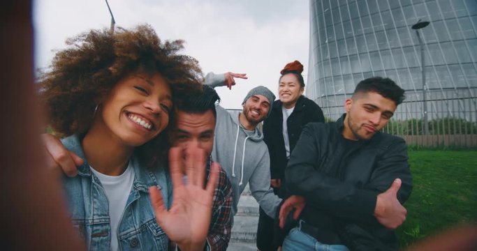 Slow motion of group of young friends of different ethnicities are having fun and making a selfie together with cellular phone in a city center with skyscrapers