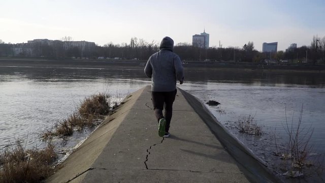 Fitness runner jogging and celebrating on finishing a goal at the river side of Vistula