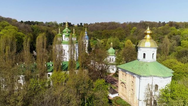 Church in the ity Garden on the Hill. Vydubitsky monastery on a sunny spring day. Kyiv, Ukraine. An opening view from the Botanical garden to the Vydubitsky Monastery.  Orthodox monastery 
