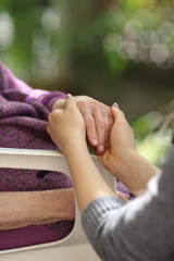 Young caregiver holding seniors hand. Elderly concept
