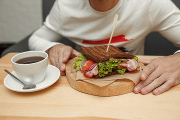 Man in cafe take his order sandwich and coffee
