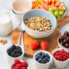 Raw vegan gluten and grain free paleo granola or muesli made from nuts. Fruit berries platter, strawberries blueberries raspberries peach figs red currant, side view, selective focus