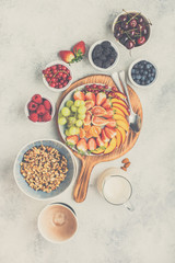 Raw vegan grain free paleo style granola or muesli made from nuts. Fruit berries platter, strawberries blueberries raspberries peach figs red currant, overhead view, toned, selective focus