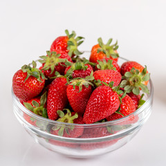 Fresh strawberry in a bowl on a wooden background.