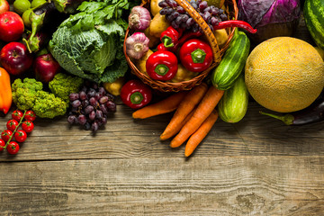fresh crop of different vegetables on a wooden table, top view with free space for text