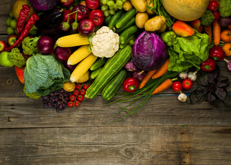fresh crop of different vegetables on a wooden table, top view with free space for text