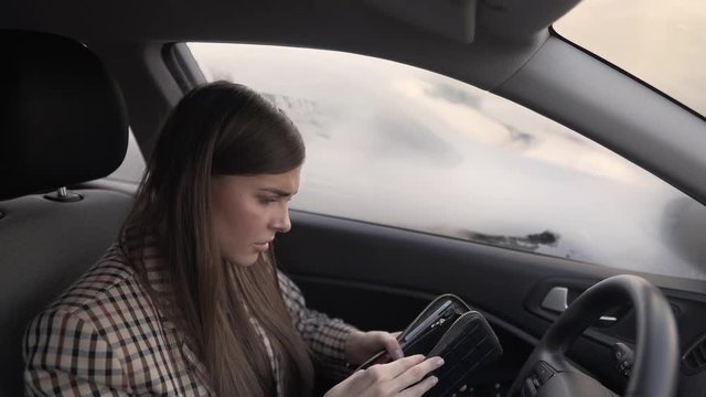 Very sexy brunette with long hair sitting in car, opening empty wallet, forgetting money and credit cards. Girl getting upset and hitting/punching the driving wheel and desperately leaning on backseat