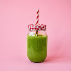 Healthy green smoothie  in a jar mug on pink background. Copy space