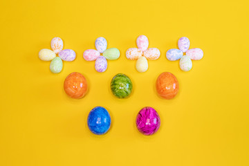 A lot of colorful Easter eggs on a yellow background. Top view, minimal Easter concept. Happy Easter card  with free, empty space.