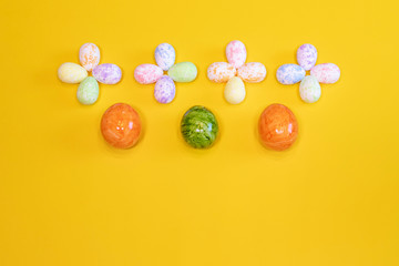 A lot of colorful Easter eggs on a yellow background. Top view, minimal Easter concept. Happy Easter card  with free, empty space.