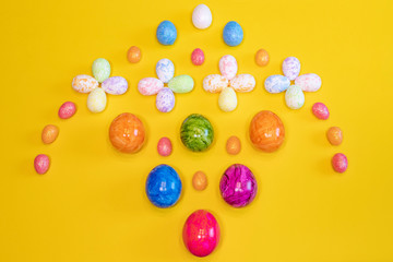 A lot of colorful Easter eggs on a yellow background. Top view, minimal Easter concept. Happy Easter card  with free, empty space.
