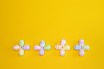 A lot of colorful Easter eggs on a yellow background. Top view, minimal Easter concept. Happy Easter card  with free, empty space.