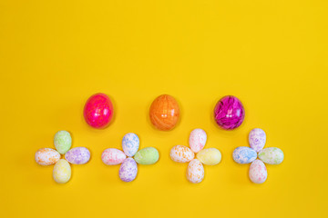 A lot of colorful Easter eggs on a yellow background. Top view, minimal Easter concept. Happy Easter card  with free, empty space.