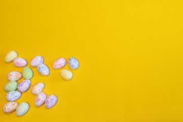 A lot of colorful Easter eggs on a yellow background. Top view, minimal Easter concept. Happy Easter card  with free, empty space.