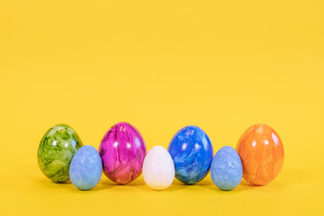 Fototapeta na wymiar Seven colored Easter eggs on a yellow background. Easter eggs stand in a row. Happy Easter card with free, empty space.