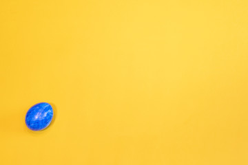 Blue Easter egg isolated on yellow background. Top view. Minimal Easter concept. Happy Easter card  with free, empty space.