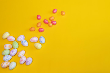 A lot of colorful Easter eggs on a yellow background. Top view, minimal Easter concept. Happy Easter card  with free, empty space.