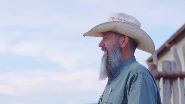 Slow motion medium shot of a cowboy with a long beard on his ranch having a conversation, 23.98 fps, 4K.