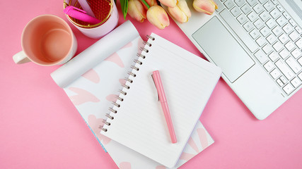 Ultra feminine cluttered pink desk workspace with touch screen laptop closeup, overhead flatlay.