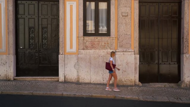 A Girl is walking through the frame in front of an iconic Wall in Lisbon, Portugal.