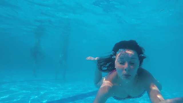 Drowning teen swimming in panic underwater in pool making bubbles, slow motion