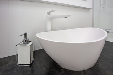 Soap and shampoo dispensers near Ceramic Water tap sink with faucet in expensive loft bathroom