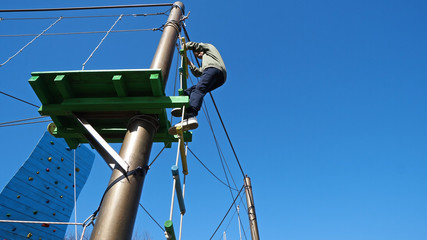 Happy child, healthy teenager school boy enjoying activity in a climbing adventure park on a summer day