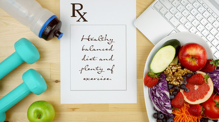 Prescription for good health overhead with stethoscope, healthy fresh food and exercise equipment.