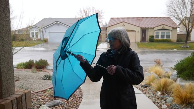 A Pretty Middle Aged Woman Walking In Out Of The Winter Rain And Putting Away Her Blue Umbrella In A Neighborhood SLOW MOTION.