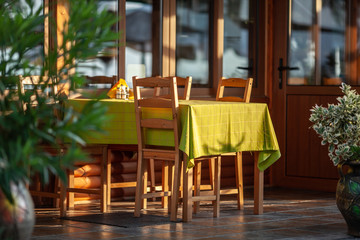 A table on a summer cafe terrace - covered with morning sunlight and a light-green tablecloth