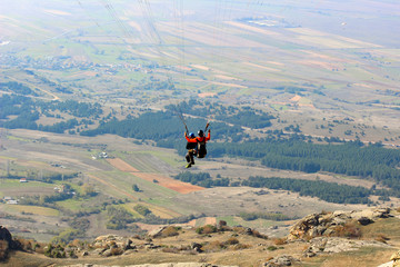 Paraglider tandem taking off mountain cliff