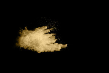 Golden powder explosion on black background. Freeze motion.