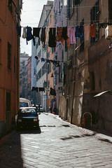 A sunlit authentic narrow Naples street with clothes, hanging on a rope, stretched across the street