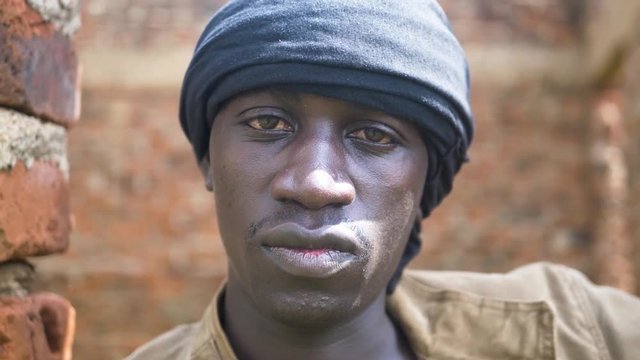 A tight close up shot of a young African gangster with a head band on in rural Africa.