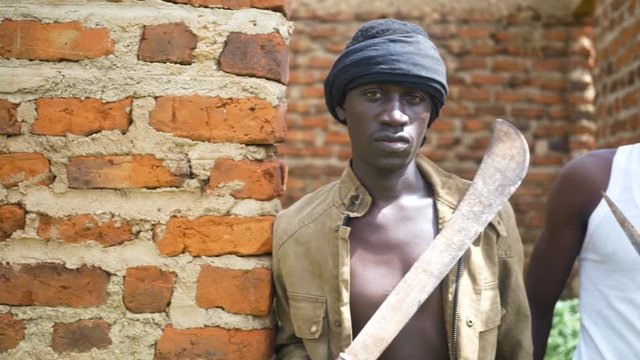 A pan shot of two young African gangsters holding weapons in an abandoned building.