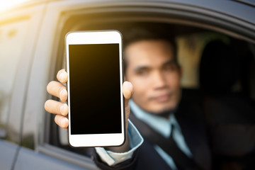 Businessman sitting in car holding mobile smart phone