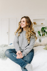 Beautiful young caucasian European woman casually sitting on the bed