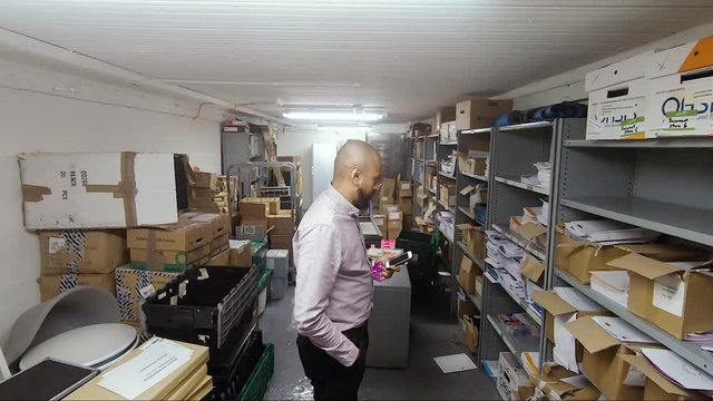 Asian Indian male looking for something in office storeroom in basement