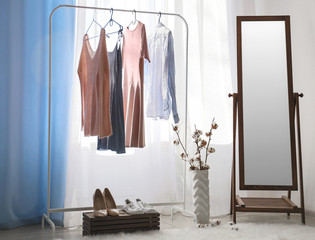 Fototapeta na wymiar Big mirror with female clothes in interior of room