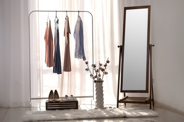 Big mirror with female clothes in interior of room