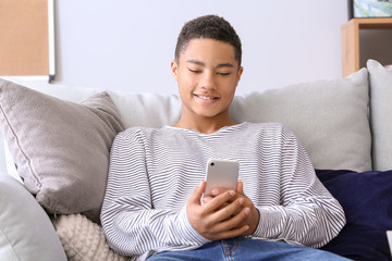 African-American teenage boy using mobile phone at home