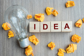 IDEA text wood cube and crumbled paper with lightbulb on wooden table background. Creative, Innovation, Imagination, inspiration, Solution, Strategy and GOAL concept