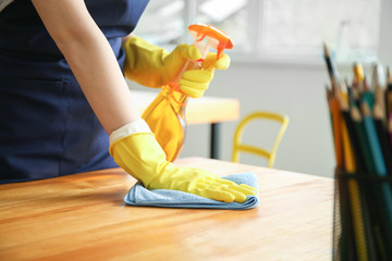 Female janitor cleaning table in office, closeup