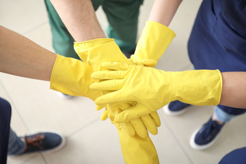 Team of janitors putting hands together