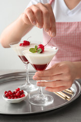 Woman decorating tasty panna cotta at table